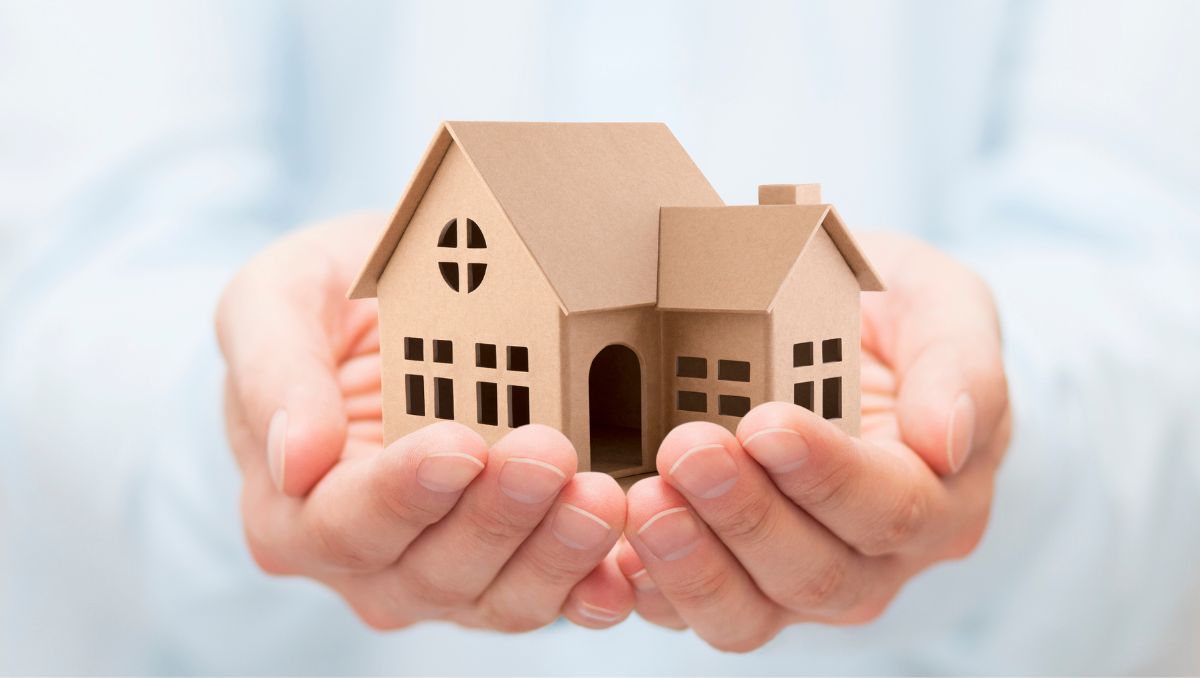 Hands holding a model house representing property protection and estate planning